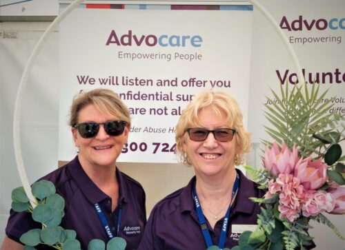 Two Advocare workers pose in front of branded sign at event