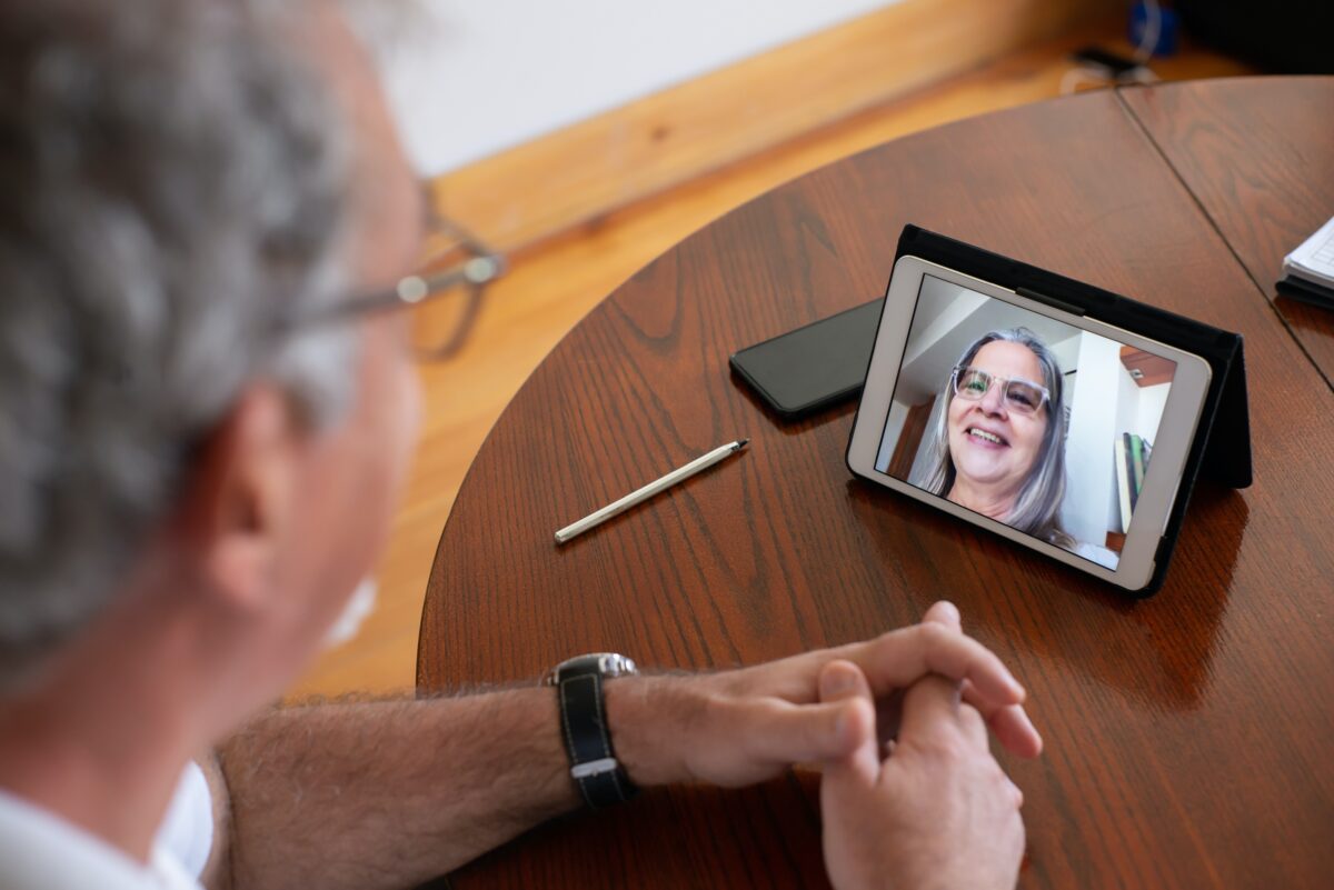older man video chats with woman on tablet device